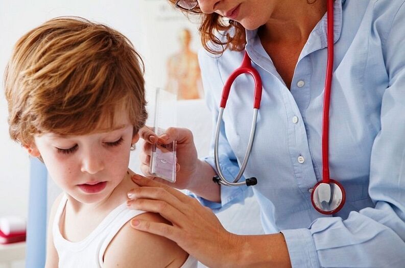 The doctor examines a child's papilloma on the body